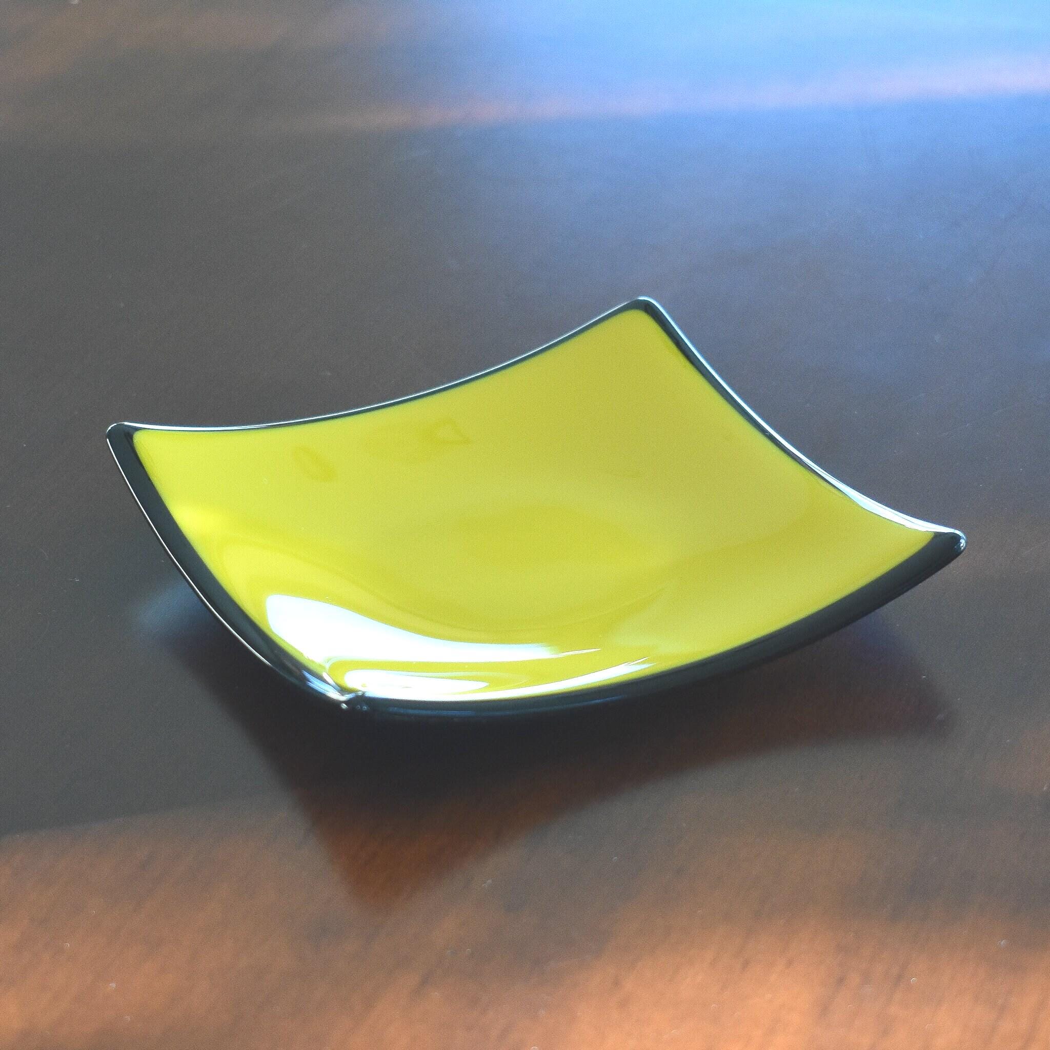 Six inch square fused glass tray with sloped corners. Yellow in center, trimmed and backed with black.