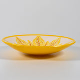 A yellow glass bowl with a white interior and a stylized sunflower design in yellow, orange, and brown.