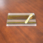 Rectangular cheese tray made with gold, black and clear iridescent fused glass. Gold spreader knife laying on top.