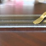 A clear glass cheese board with a gold-toned design and a gold-colored cheese knife.