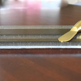 A clear glass cheese board with a gold-toned design and a gold-colored cheese knife.