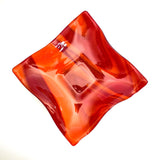 Large square glass bowl with wavy edges and a square center foot, viewed from above on a white surface, showing the square foot and the general shape.