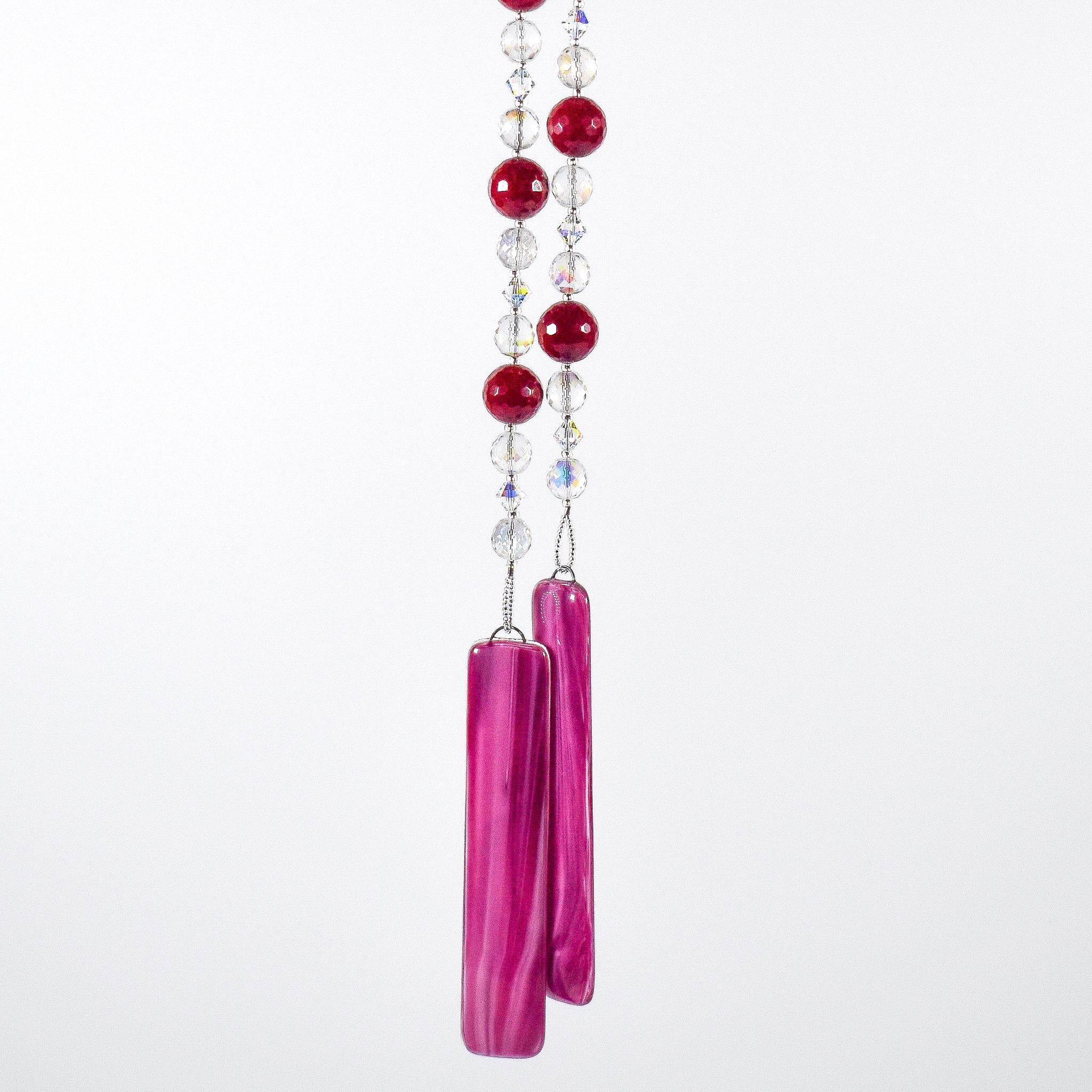 Large cranberry red jade stones beaded with glass and crystals, anchored by two pieces of dark cranberry pink fused glass, hanging vertically against white background.