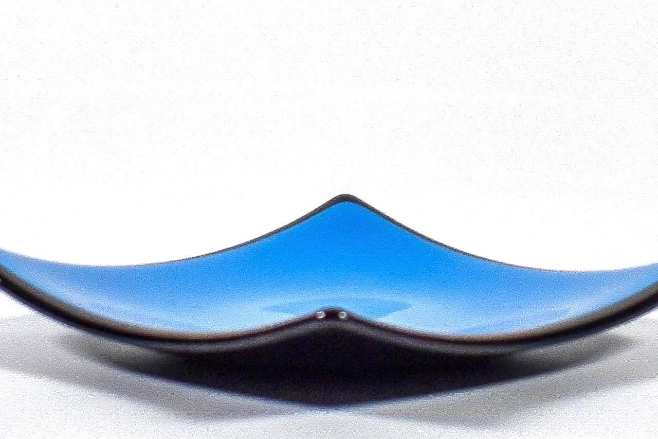 Square fused glass dish with solid blue center, black trim and black base, sitting white surface.
