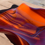 Close up view of the glass used to make the wave edge bowl. Swirls are made of opaque orange and transparent cherry red glass.