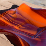 Close up view of the glass used to make the wave edge bowl. Swirls are made of opaque orange and transparent cherry red glass.