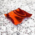 Large square glass bowl with wavy edges and a square center foot, viewed at an angle sitting on gray speckled counter top, inside.