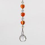 A crystal sun catcher with three orange heart-shaped beads. The suncatcher ends with a clear crystal ball.