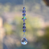 Small sun catcher with six purple crystal cube beads, a single crystal cross in paradise shine color, anchored by glass crystal prism.