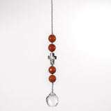 Small sun catcher hanging in front of white background with 4 goldstone beads flanking a golden glass crystal cross. Attached to a round glass crystal prism.