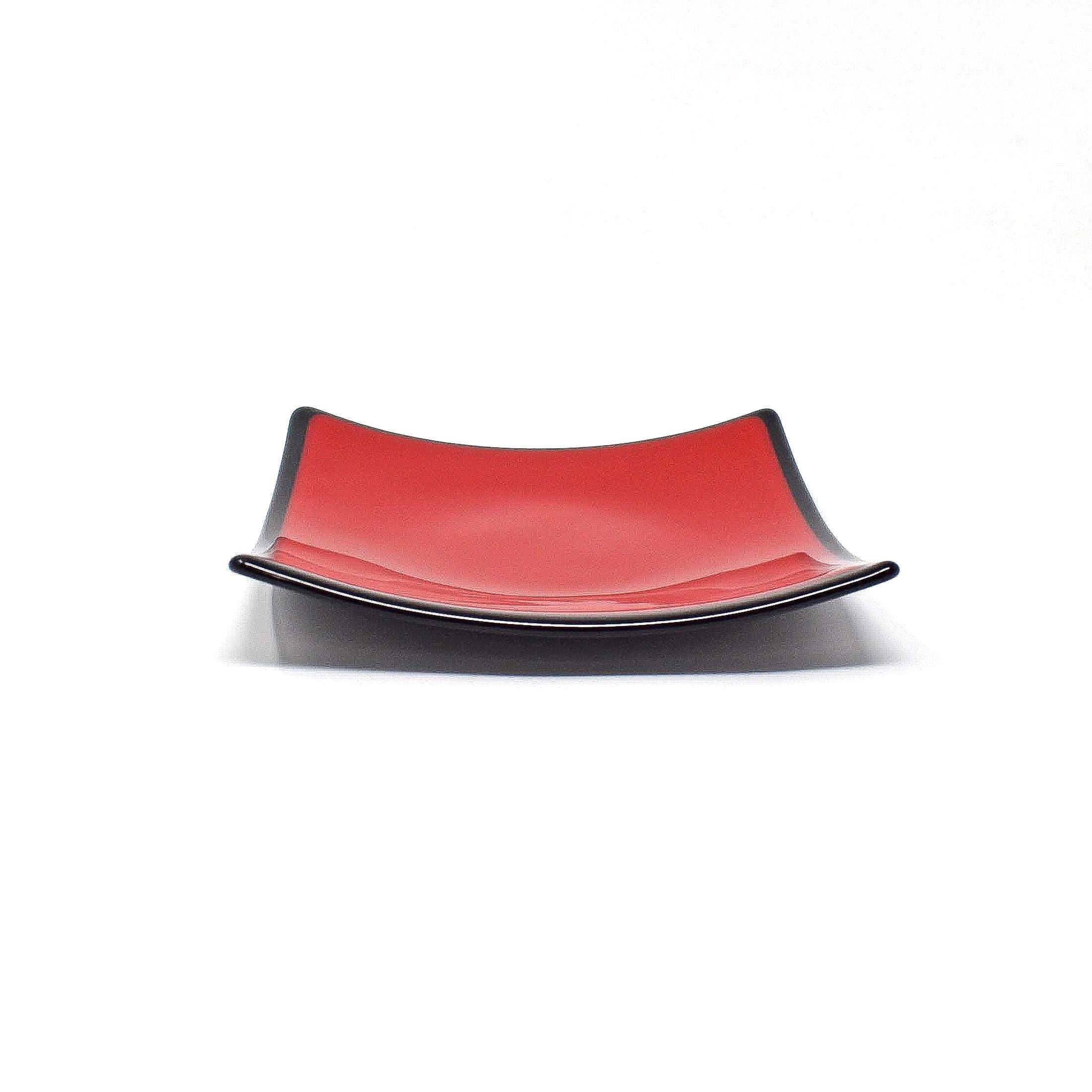 A red glass dish with a black rim. The dish is slightly curved and has a glossy finish.