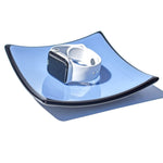 A white Apple Watch with a white band sits on a blue and black glass dish.