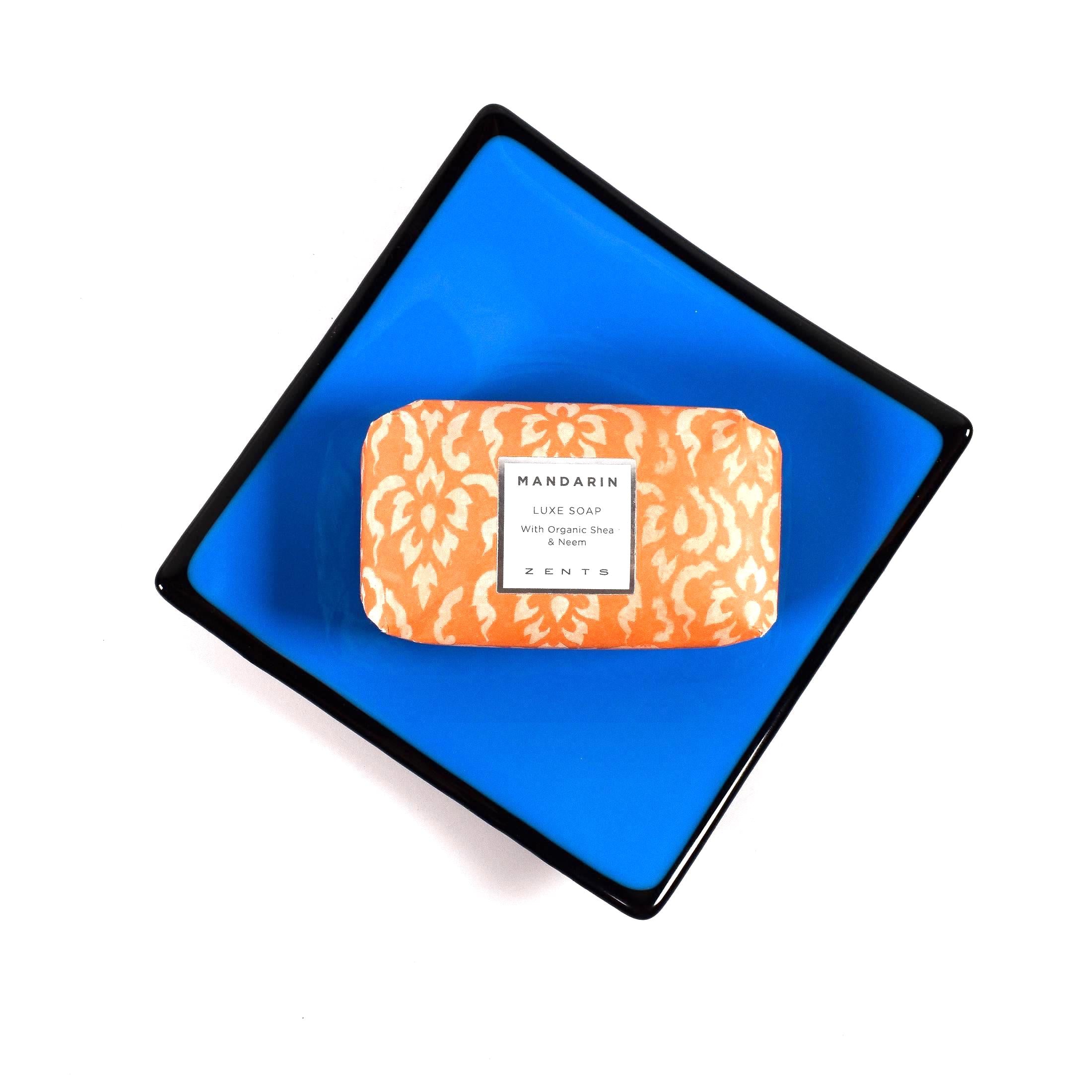 Square fused glass dish with solid blue center, black trim and black base, sitting white surface. A bar of soap is on the tray showing how it would work as a soap dish.