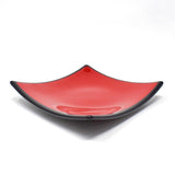 A square-shaped glass dish with a red interior and a black rim.