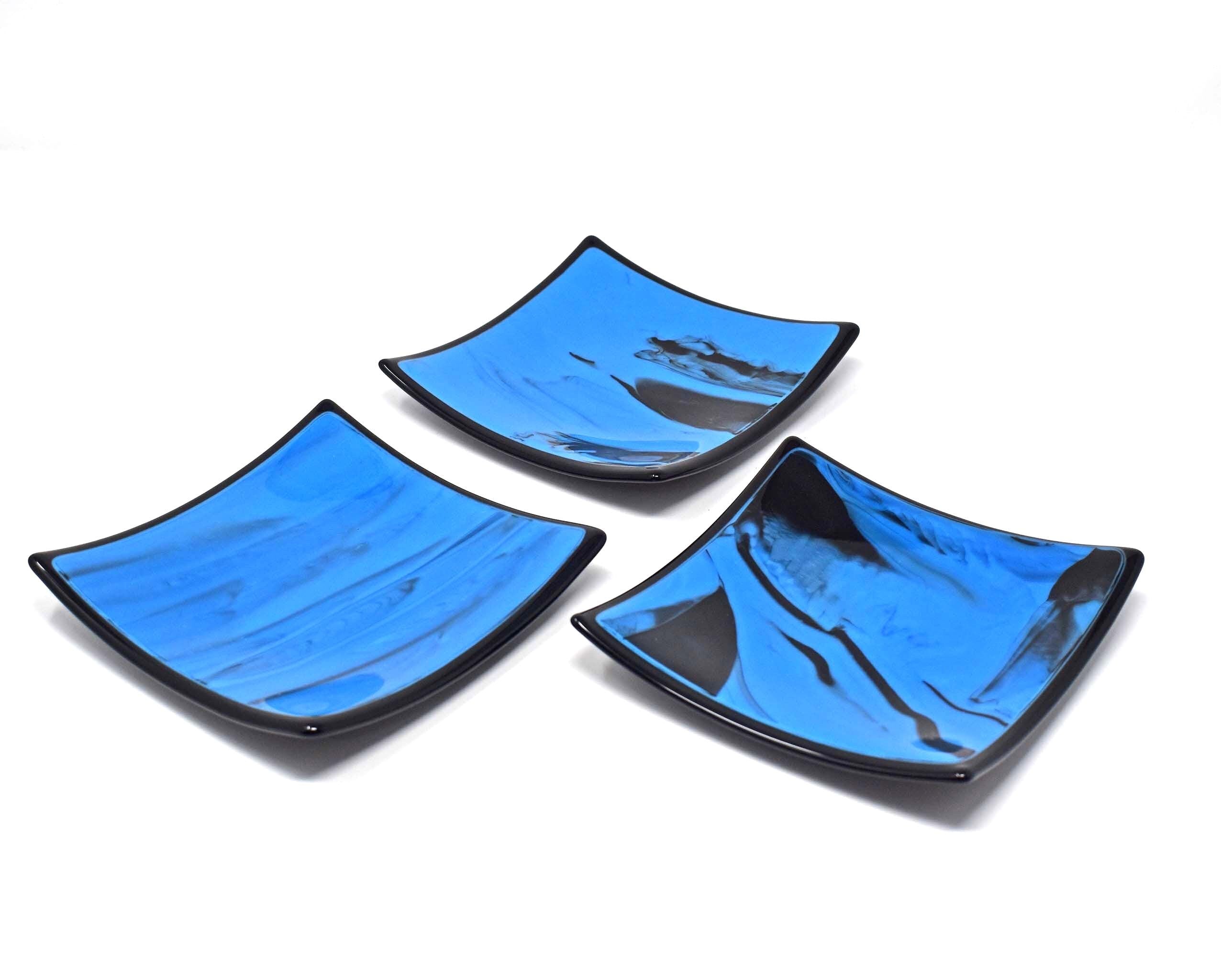 Three different six inch square glass trays. Center of each tray is a medium blue with black streaks. Trim is solid black. On white background.