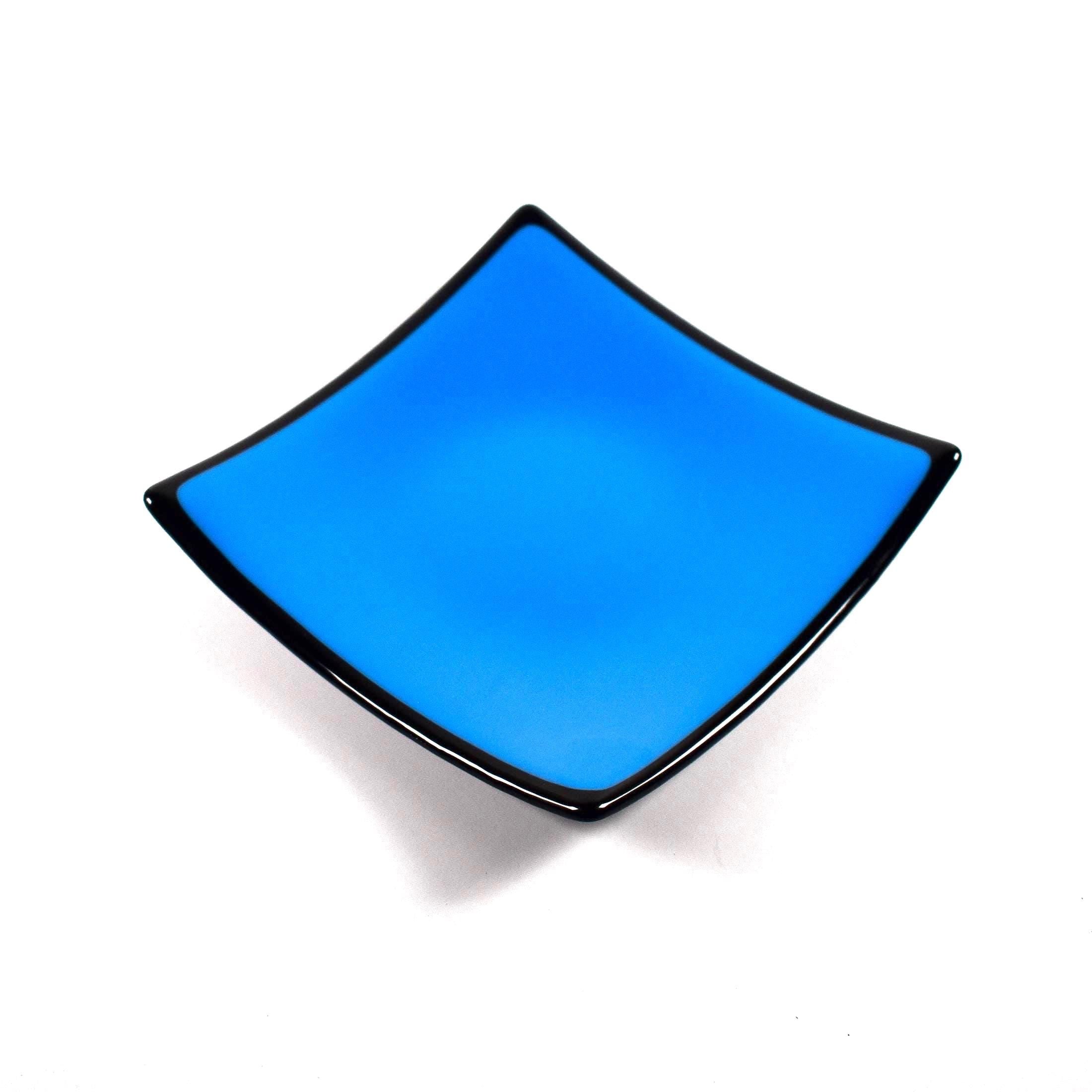 Square fused glass dish with solid blue center, black trim and black base, sitting white surface.