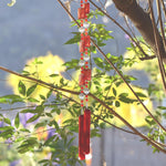 Red wind chime hanging from tree. Chime is made of fused glass, glass beads, stainless steel wire and acrylic rectangular beads.