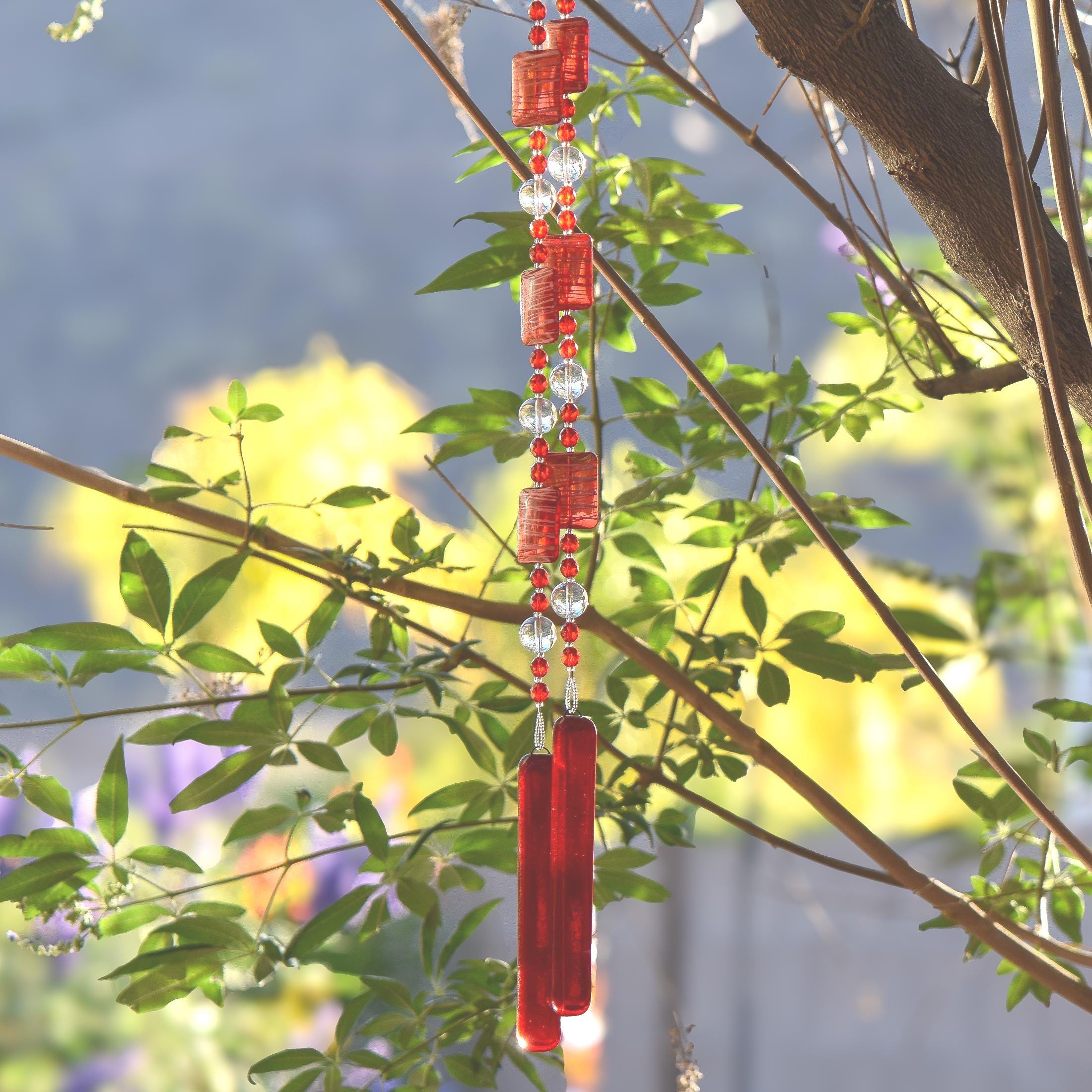 Red wind chime hanging from tree. Chime is made of fused glass, glass beads, stainless steel wire and acrylic rectangular beads.