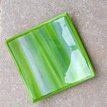 Six inch square fused glass tray in lime green, amazon green and white with amazon green trim, viewed from the top. Tray is sitting on neutral tile.