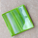 Six inch square fused glass tray in lime green, amazon green and white with amazon green trim, viewed from the top. Tray is sitting on neutral tile.
