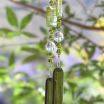 Green wind chime hanging from tree. Chime is made of fused glass, glass beads, stainless steel wire and acrylic rectangular beads.