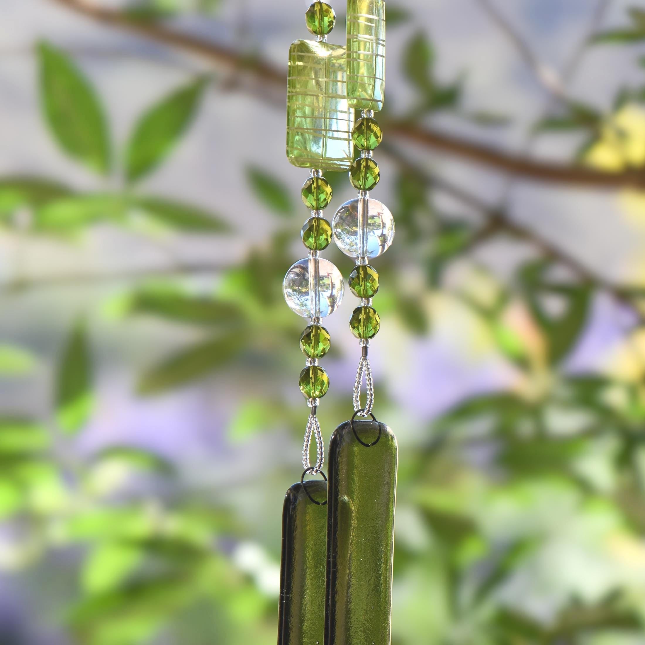 Green wind chime hanging from tree. Chime is made of fused glass, glass beads, stainless steel wire and acrylic rectangular beads.