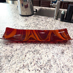 Large red and orange channel tray in fused glass resting on white and black kitchen island.