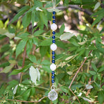 Quartz and Aqua Glass Sun catcher hanging vertically against background of leaves.