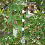 Quartz and Aqua Glass Sun catcher hanging vertically against background of leaves.