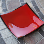 Red, square dish with black trim on stone table