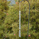 Small aqua glass beads paired with large solid clear glass beads, strung and hanging vertically in front of shrub. Anchored by two pieces of fused glass with southwest design.