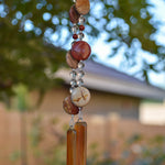 Large, flat, round Mookaite Jasper beads strung with smaller beads, hanging vertically, anchored by two pieces of amber fused glass.