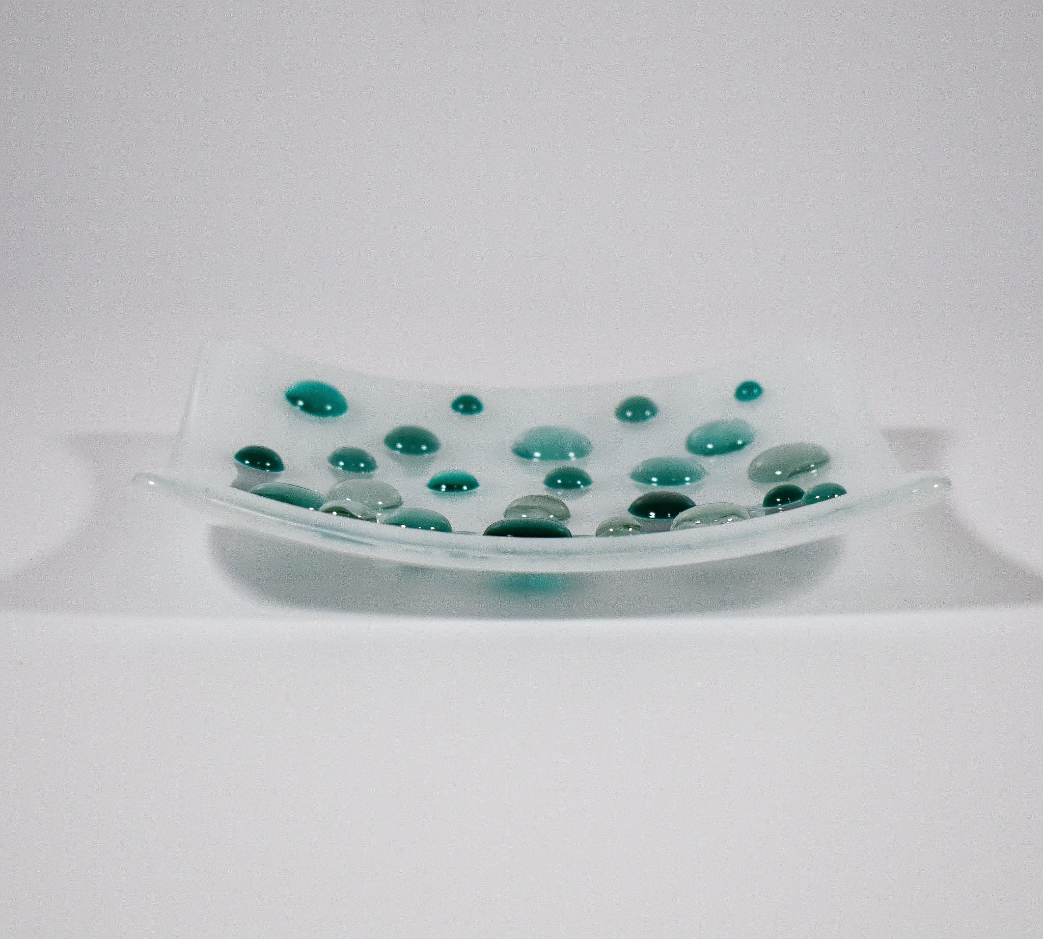 Pure white square glass dish with round glass &quot;dots&quot; in various shades of teal green. Tray is 6&quot; square with sloped corners.