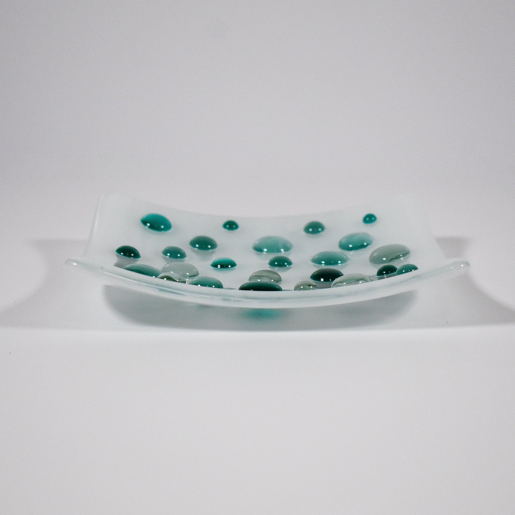 Pure white square glass dish with round glass &quot;dots&quot; in various shades of teal green. Tray is 6&quot; square with sloped corners.