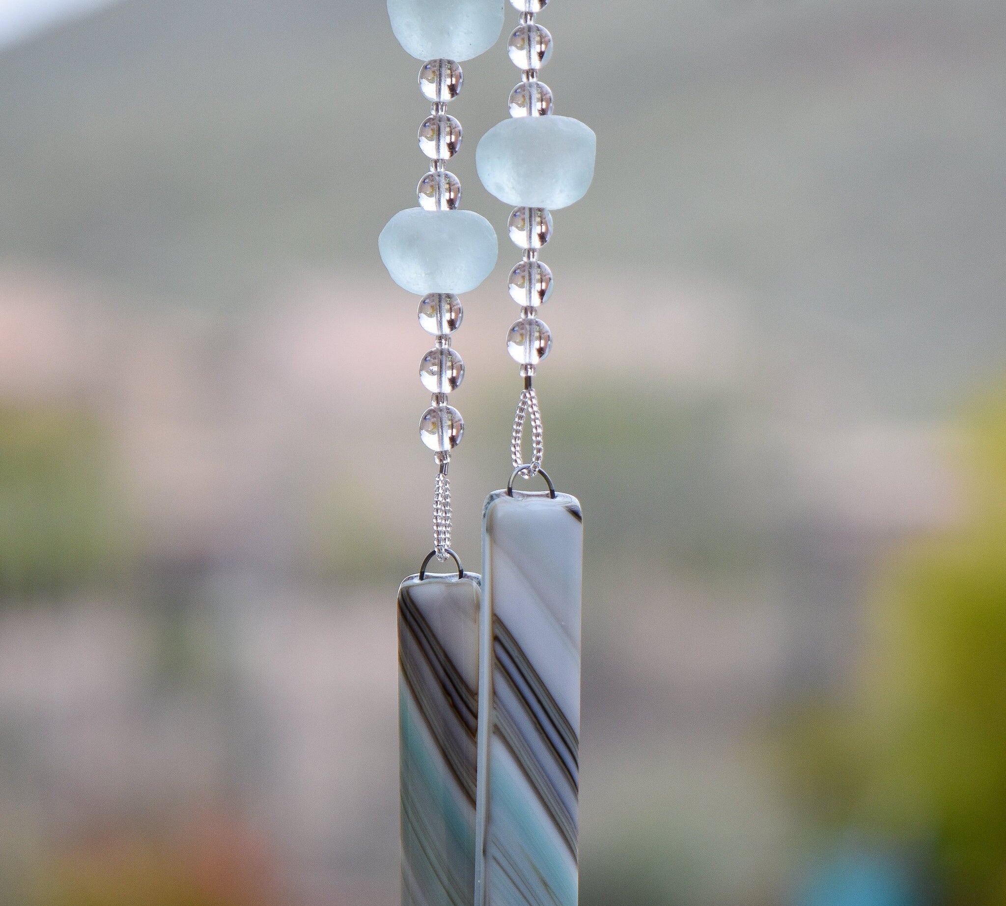 Large aqua-colored Ghana, Africa beads paired with smaller clear glass beads, hanging vertically, anchored by two pieces of fused glass with aqua, tan and gray swirl pattern