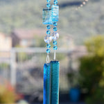 Large rectangular beads in sky blue with matching smaller round beads and large clear beads, all hanging vertically from a tree. Anchored by two pieces of sky blue fused glass